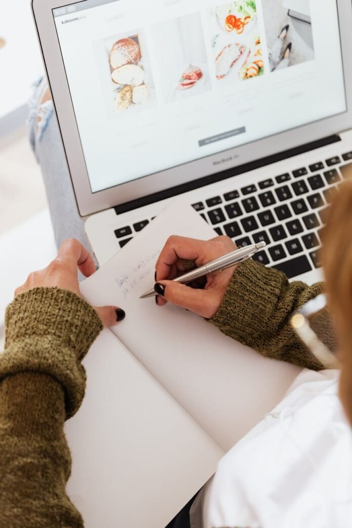 crop woman taking notes and working on laptop
