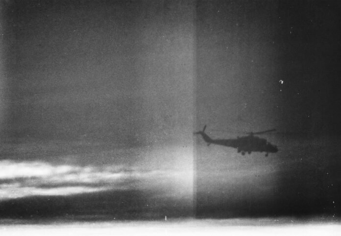 silhouette of military helicopter flying in cloudy sky