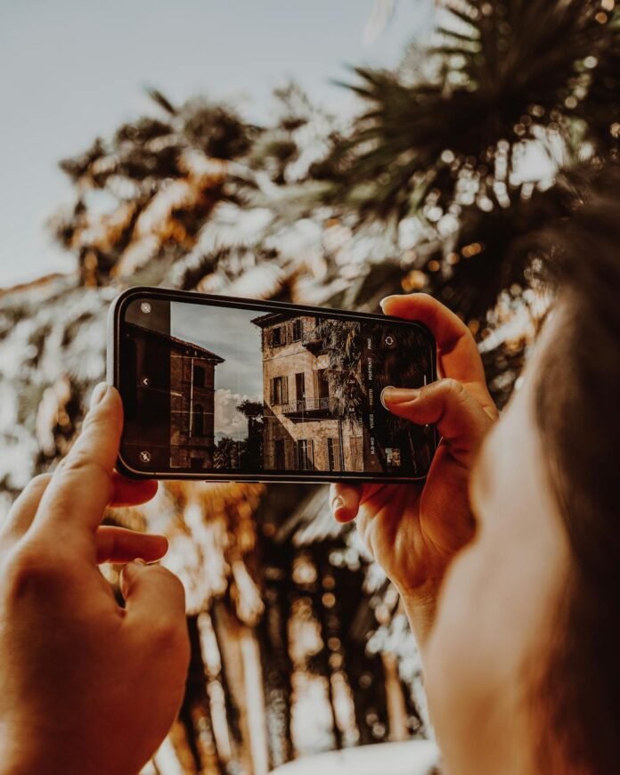 close up of a person photographing buildings and palm trees with a smartphone