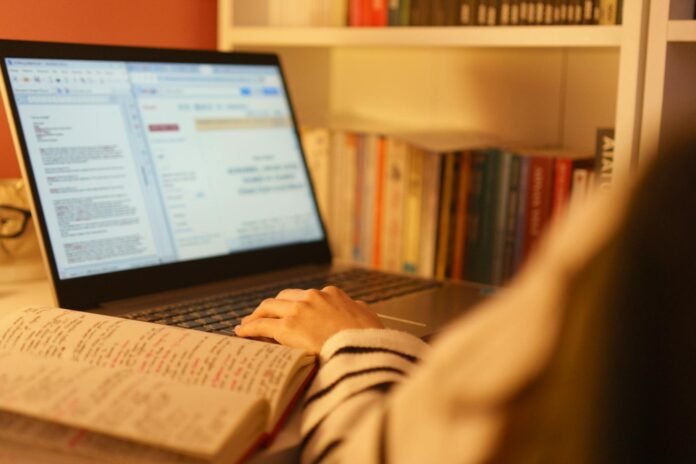 person studying with laptop and books at home