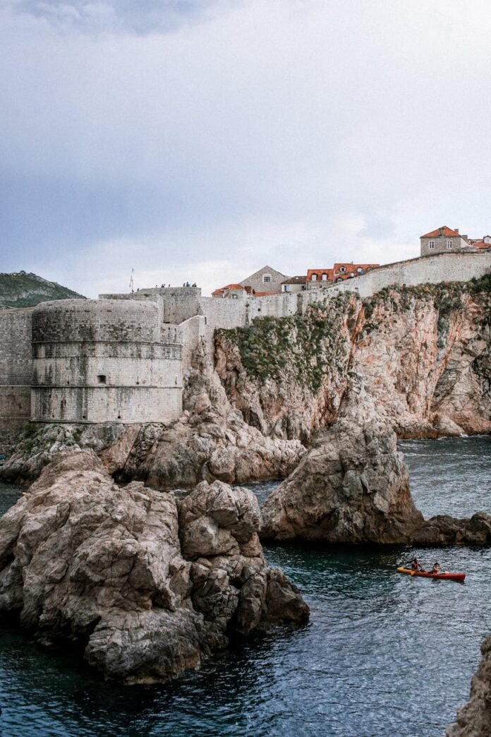 old masonry castle on ridge near sea under cloudy sky