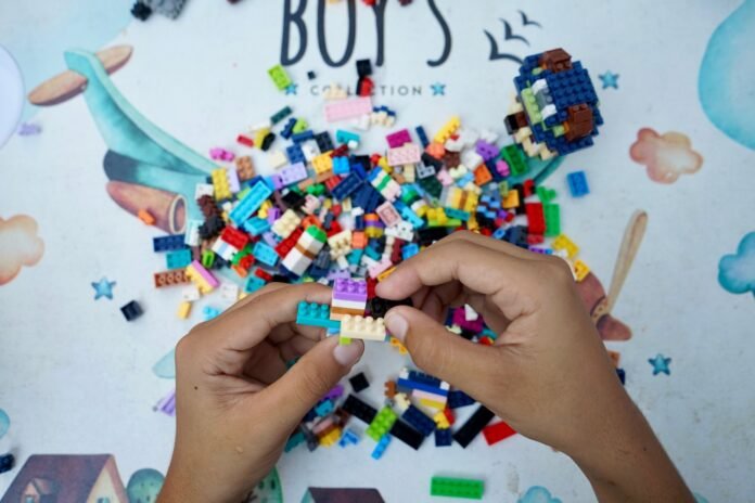 child building with colorful lego blocks outdoors