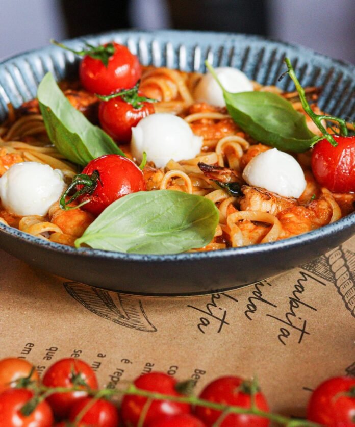 a bowl with pasta tomatoes and mozzarella