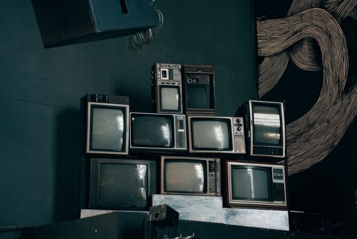stack of vintage crt televisions in dark room